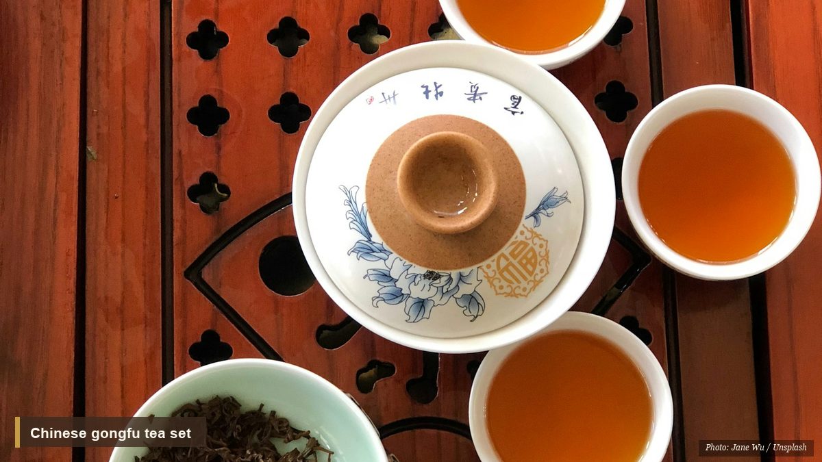 Overhead view of a Chinese gongfu tea set with amber tea and loose leaves