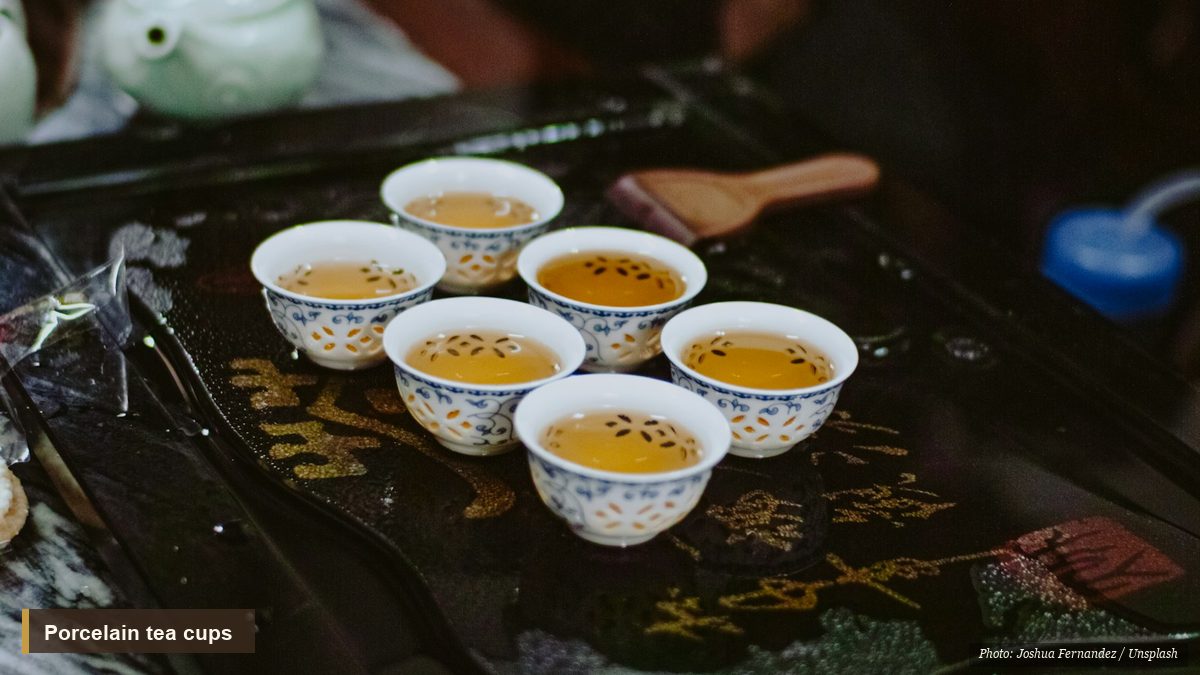 Small blue-and-white porcelain cups of pale tea on a lacquer tray