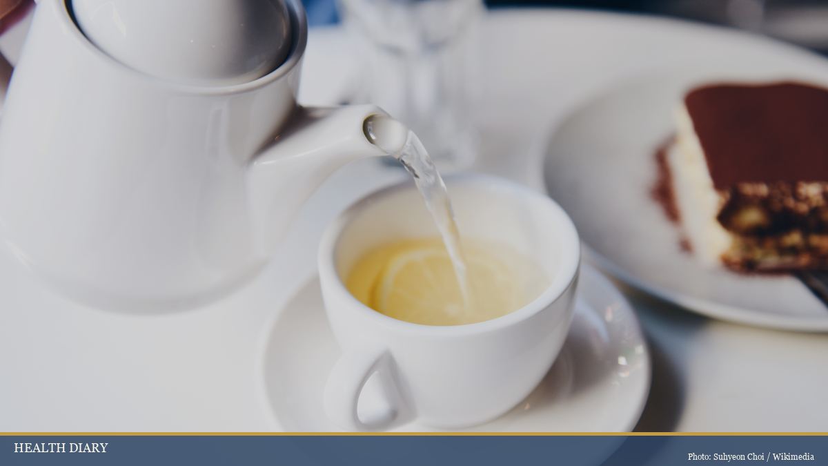 White teapot pouring fresh herbal tea into a cup as an evening wind-down ritual