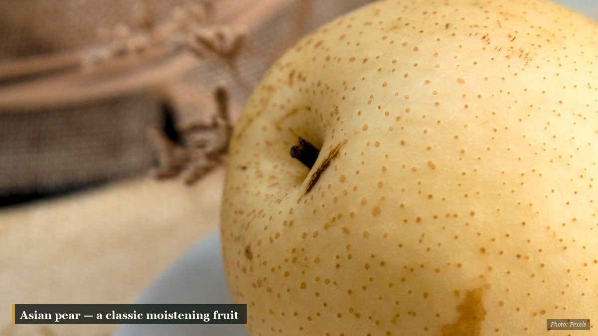 Close-up of a fresh Asian pear on a white plate in autumn light