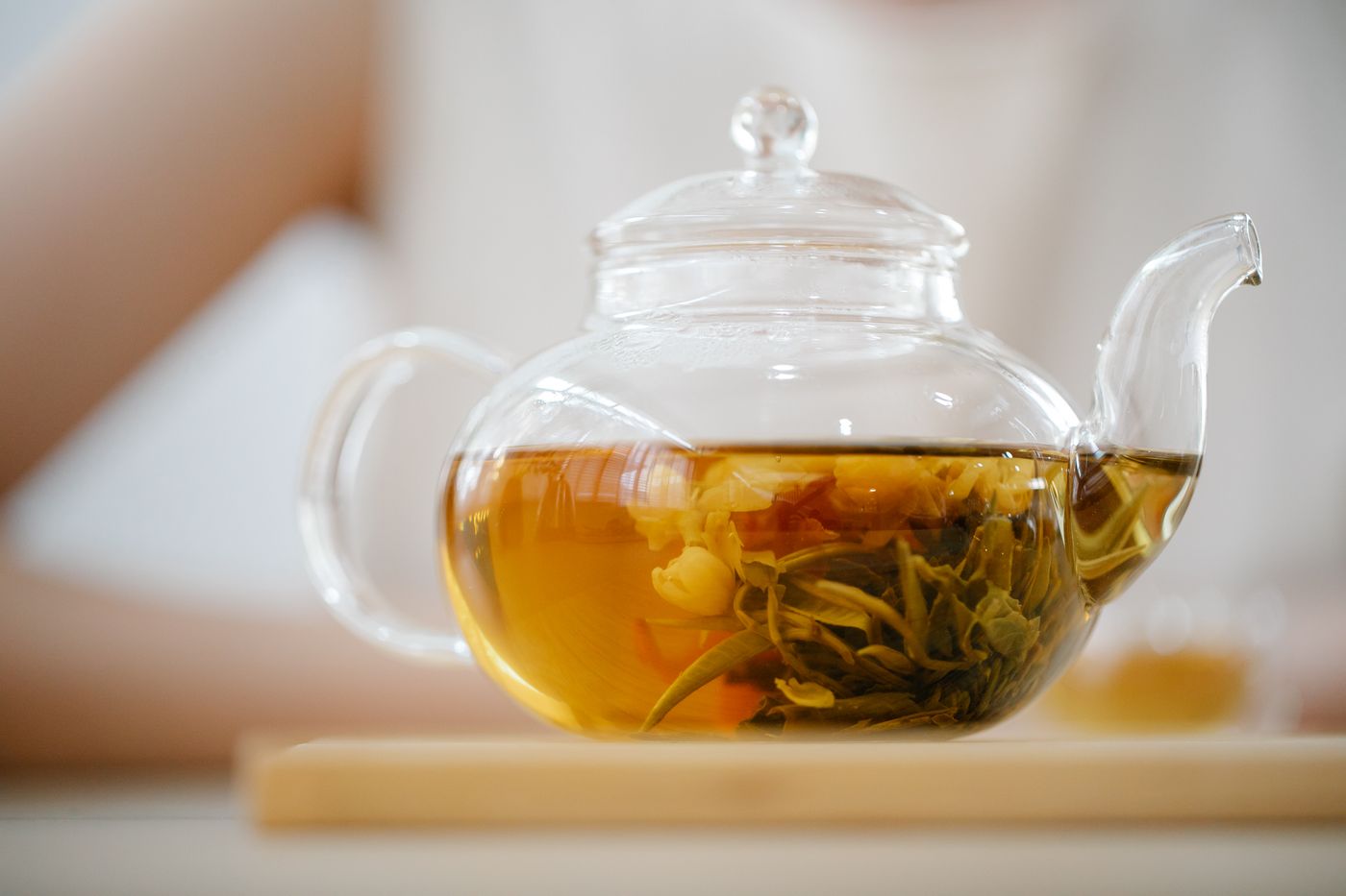 Glass teapot with brewed amber grain tea on a wooden tray