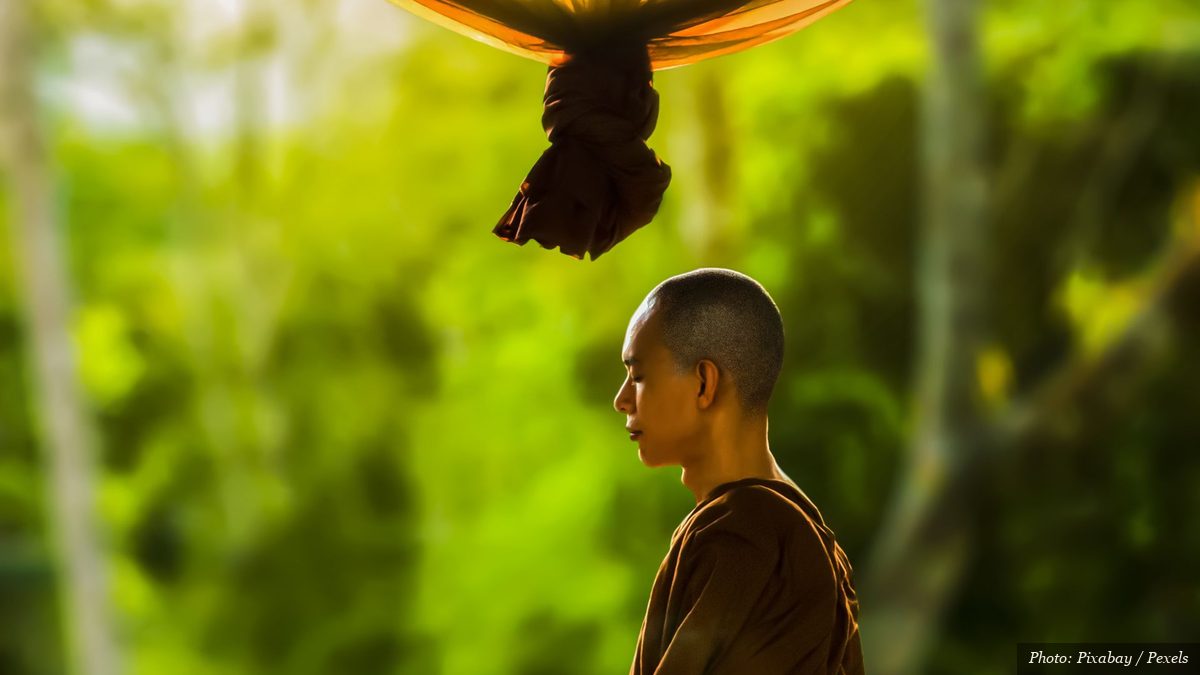 Buddhist monk in traditional robes sitting in quiet seated meditation