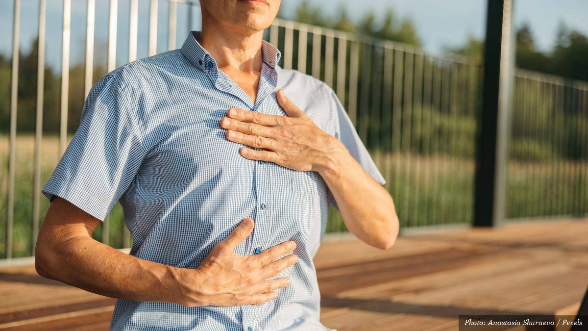 Person practicing slow abdominal breathing with one hand on the chest and one on the belly outdoors