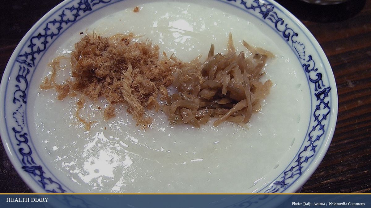 Bowl of traditional Chinese rice congee porridge with savory toppings and herbs