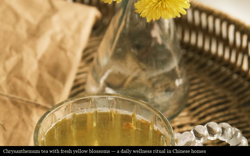 Chrysanthemum tea with fresh yellow blossoms on a wicker tray, served in a glass mug