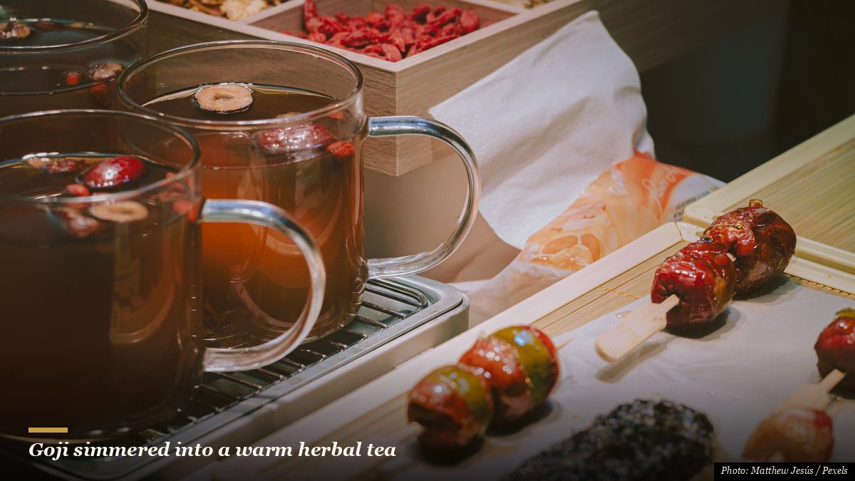 Traditional Chinese herbal tea with dried goji berries and candied fruit skewers at a market stall