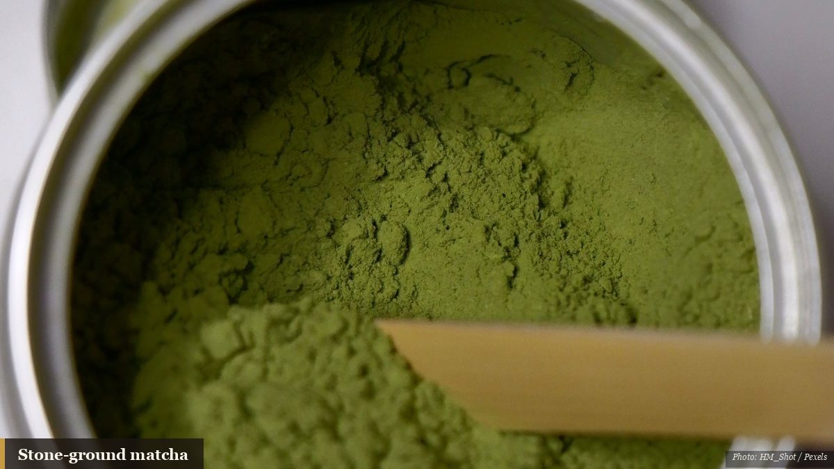 Vivid green stone-ground matcha powder in an open tin with a bamboo scoop