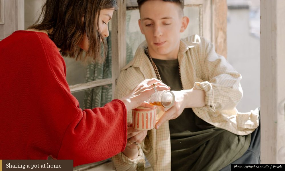 Two friends sharing cups of tea by a bright window at home