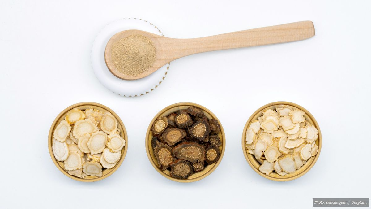 Variety of dried traditional Chinese herbs arranged in bowls and scoops