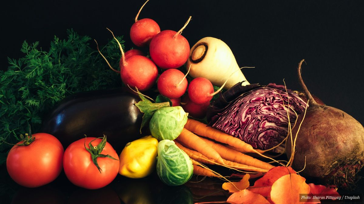 Colorful spread of red, green, yellow, white, and dark vegetables and fruits on a table