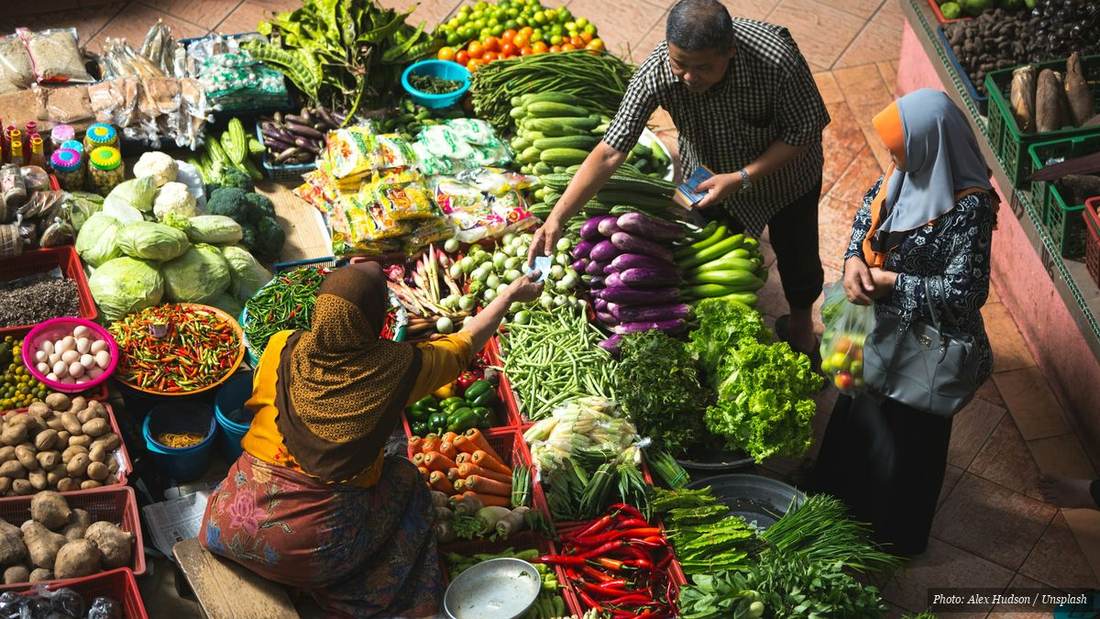 Vendors selling fresh seasonal vegetables at a Southeast Asian wet market