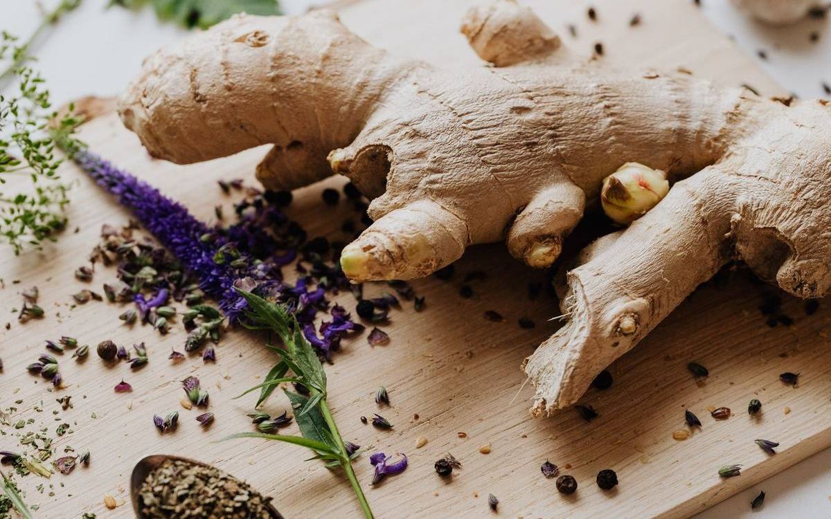 Fresh ginger root with herbs and spices on a wooden cutting board — a staple of Asian wellness cooking