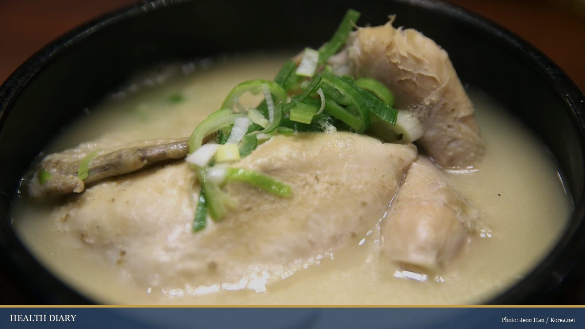 Korean samgyetang ginseng chicken soup served in a black stone bowl, topped with sliced scallions