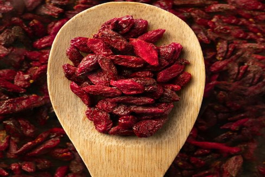 Dried goji berries (wolfberries) on a wooden spoon, showing the characteristic deep red color of quality Lycium barbarum