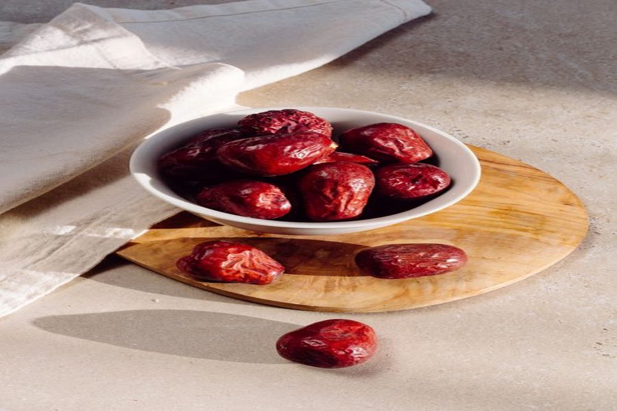 Red jujube dates (hong zao) in a ceramic bowl, a traditional companion ingredient to goji berries in Chinese wellness soups