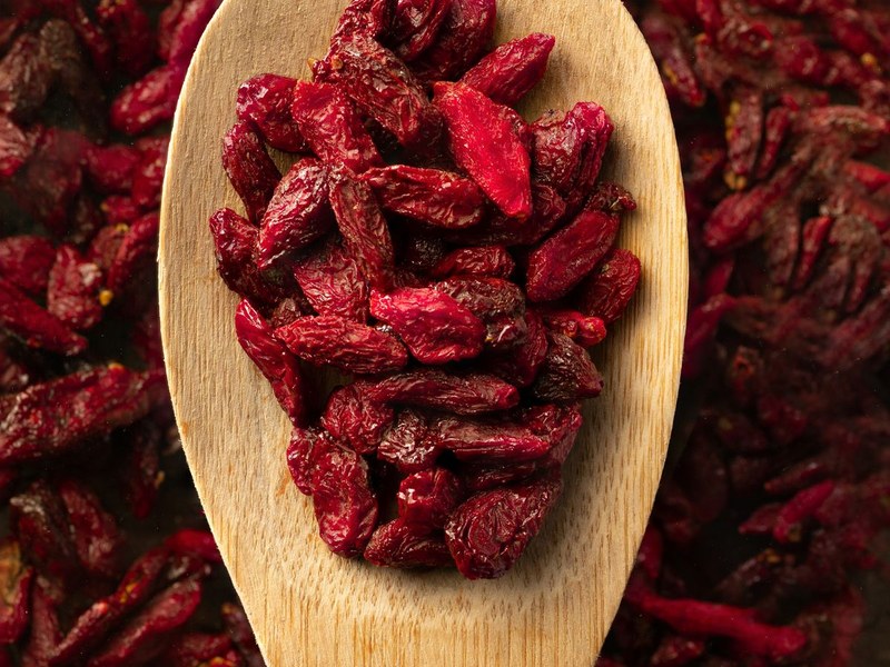 Dried goji berries on a wooden spoon — the starting ingredient for goji berry tea