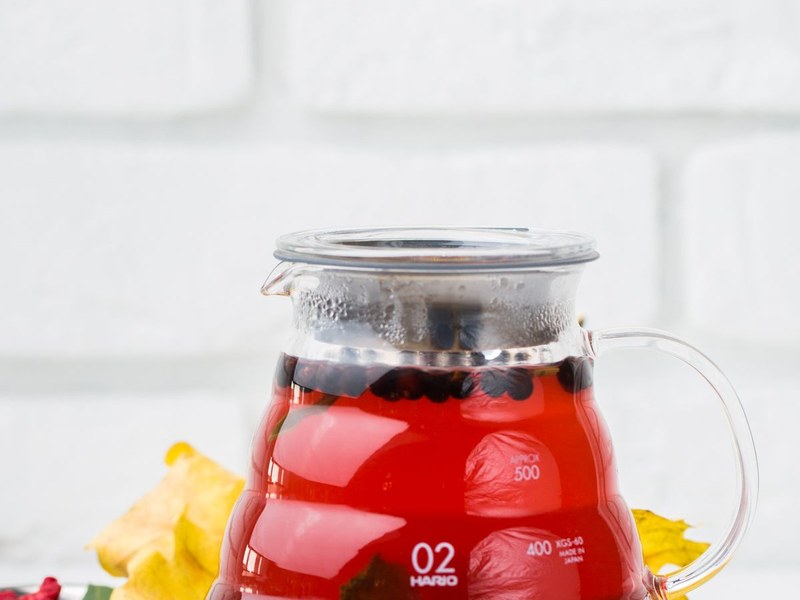 Glass teapot filled with red herbal berry tea infusion, showing the amber-red color of a well-brewed goji berry infusion