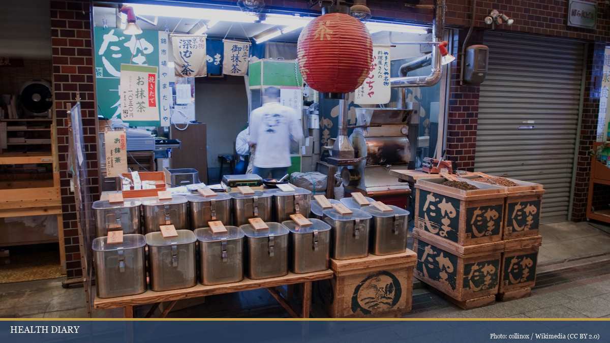 Traditional Kyoto tea shop in Nishiki market with tea barrels and worker serving green and hojicha tea selections