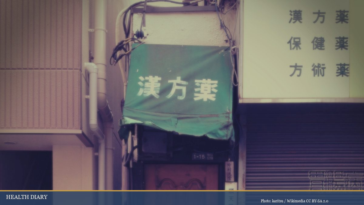 Traditional Japanese Kampo pharmacy entrance with green kanji signage in Tokyo neighborhood
