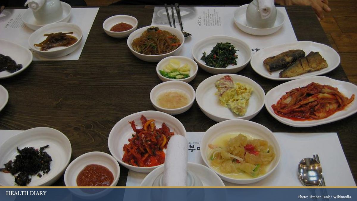 Traditional Korean banchan side dishes spread on a restaurant table with bowls and chopsticks
