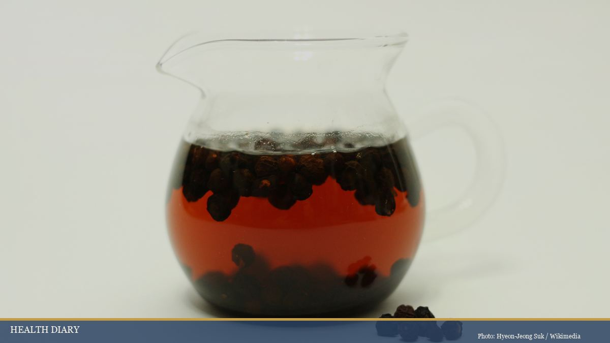 Omija-cha five-flavor berry tea infusion in a clear glass pitcher with dried Schisandra berries