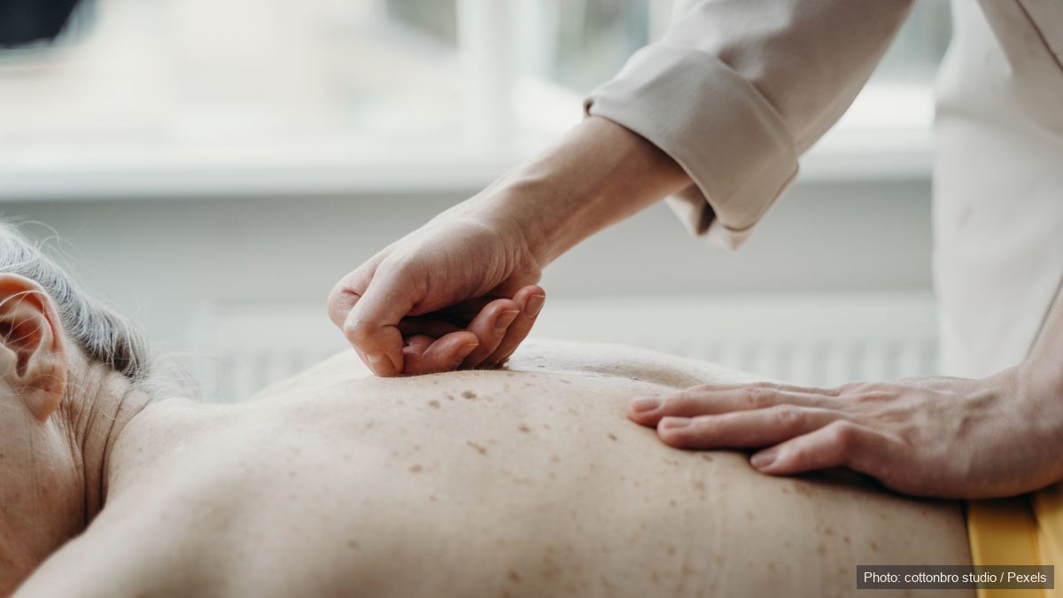Practitioner applying finger pressure along points on a client's back during tui na massage