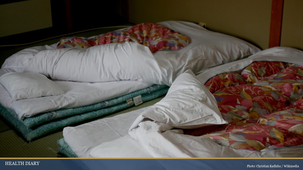 Japanese ryokan tatami room with futon bedding laid out and floral duvets for evening rest