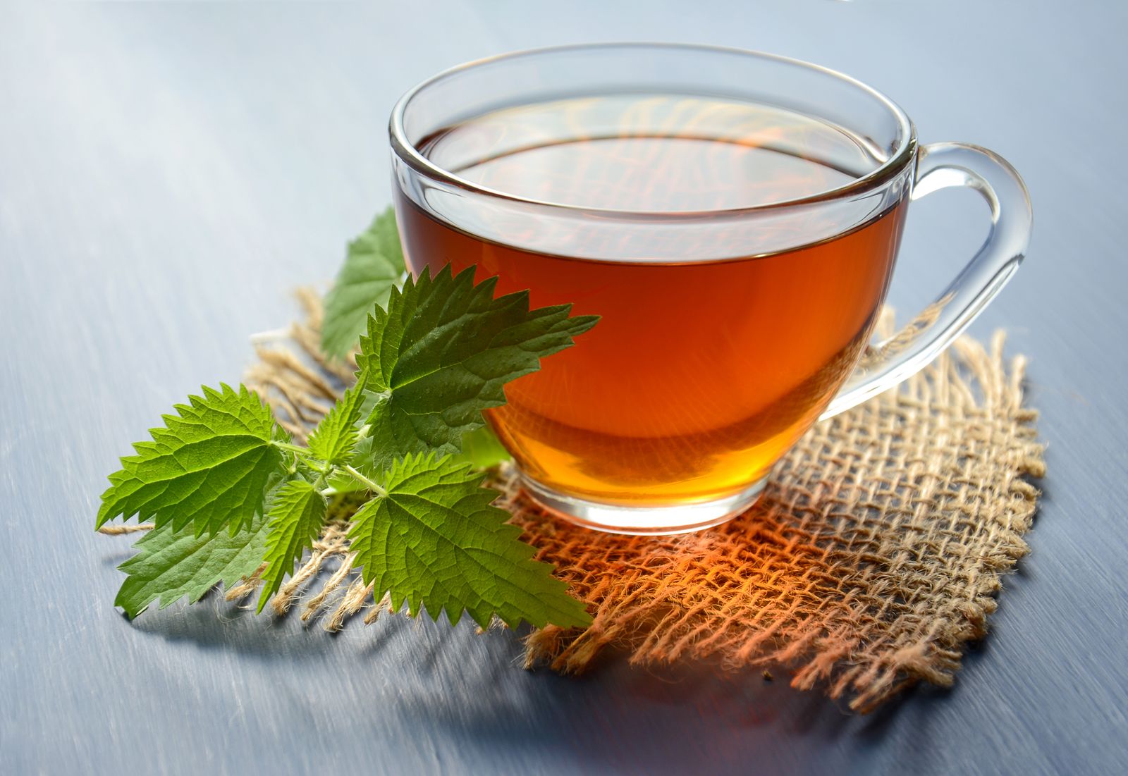 A cup of amber oolong tea with a fresh tea leaf