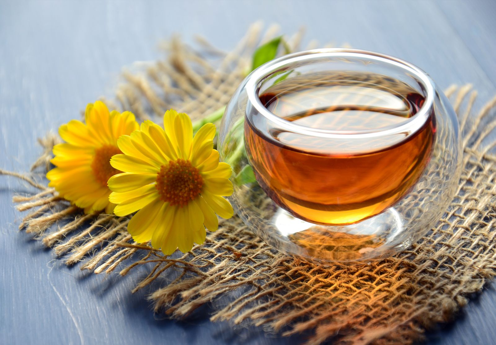 A cup of amber oolong tea beside loose leaves
