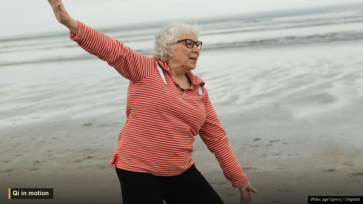 Person practicing slow tai chi movement outdoors at sunrise