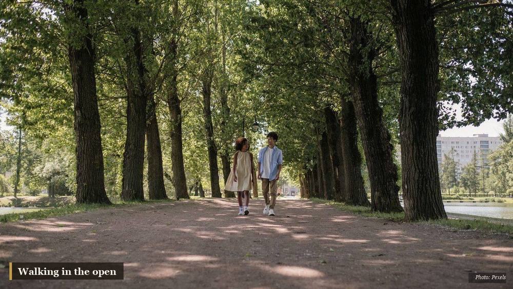 Person taking an unhurried morning walk outdoors among fresh spring greenery