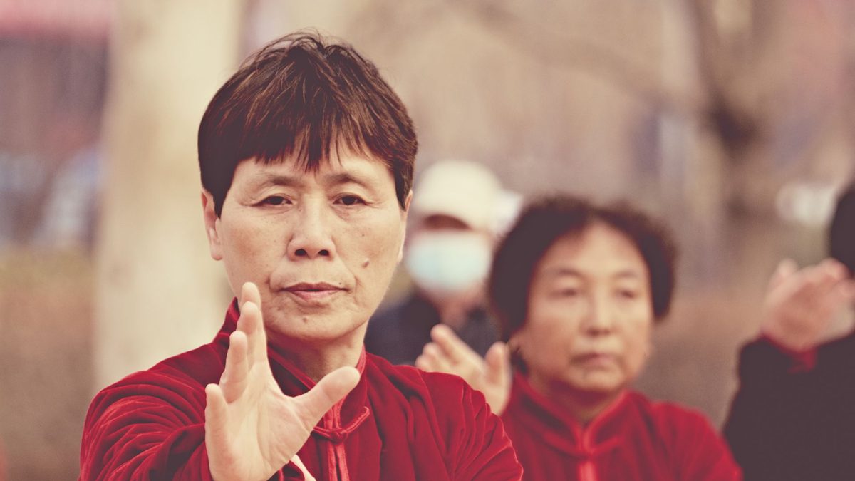 Women in red uniforms practicing a tai chi form in unison outdoors