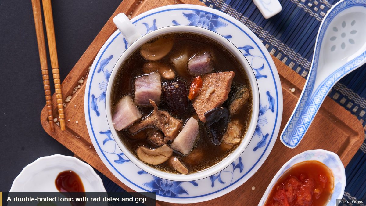 A double-boiled tonic soup with red dates and goji berries in a Chinese cup