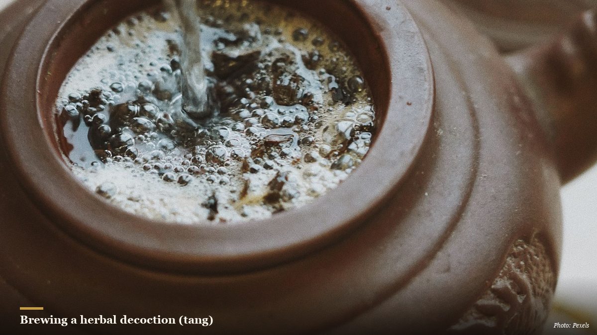 Hot water poured into a traditional clay teapot brewing Chinese herbs