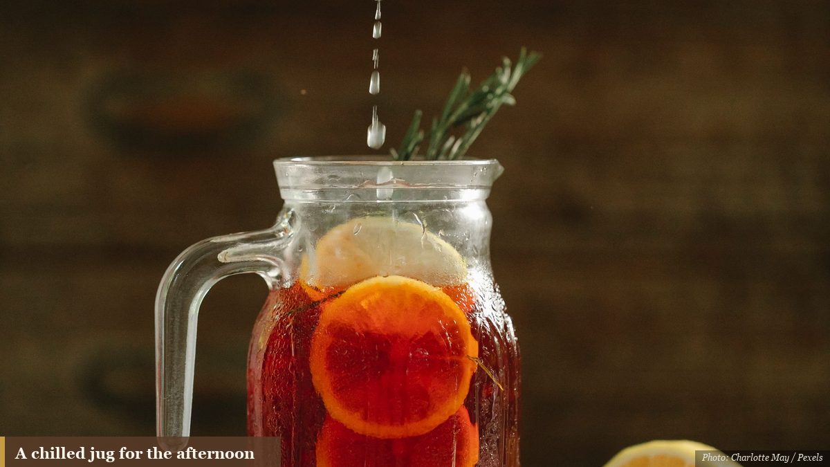 Chilled amber iced tea in a glass jug with fresh citrus on a summer table