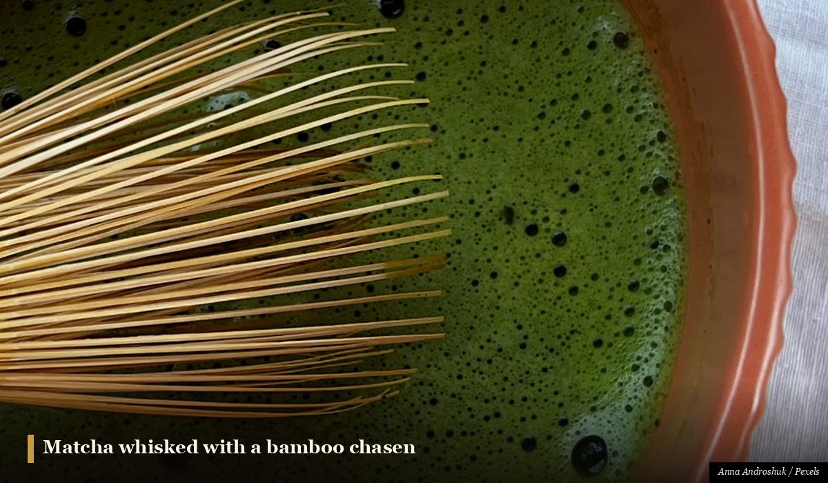 Traditional Japanese matcha green tea being whisked in a ceramic bowl with a bamboo whisk