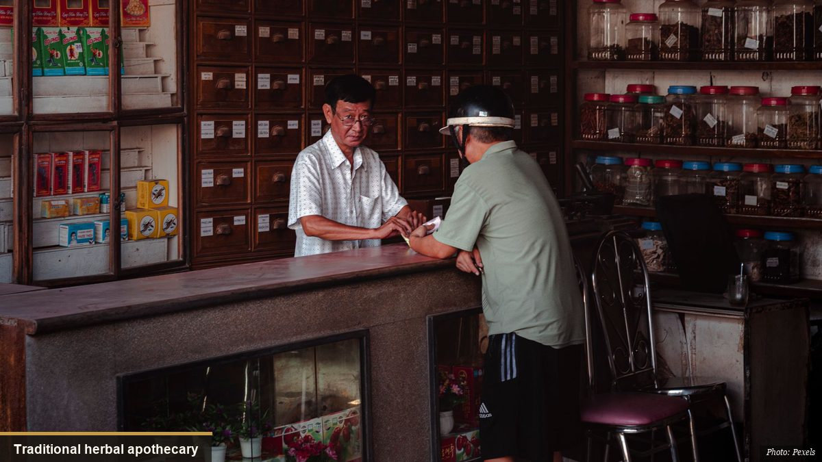 Traditional East Asian herbal medicine pharmacy with wooden drawers and glass jars of herbs