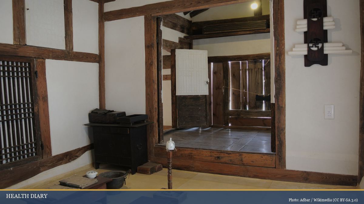 Interior of a traditional Korean hanok house with wooden frames, paper screens, low tables and warm ondol floor