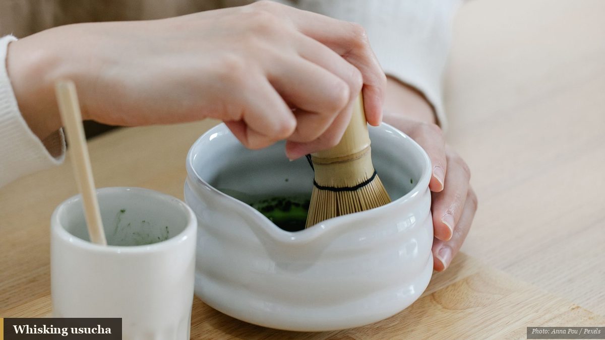 Whisking bright green matcha in a ceramic bowl during a Japanese tea ceremony