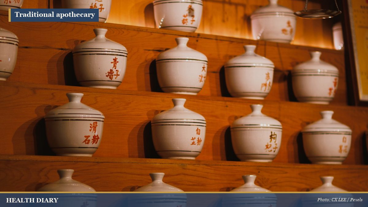 Traditional herbal apothecary jars and wooden medicine drawers on shelves