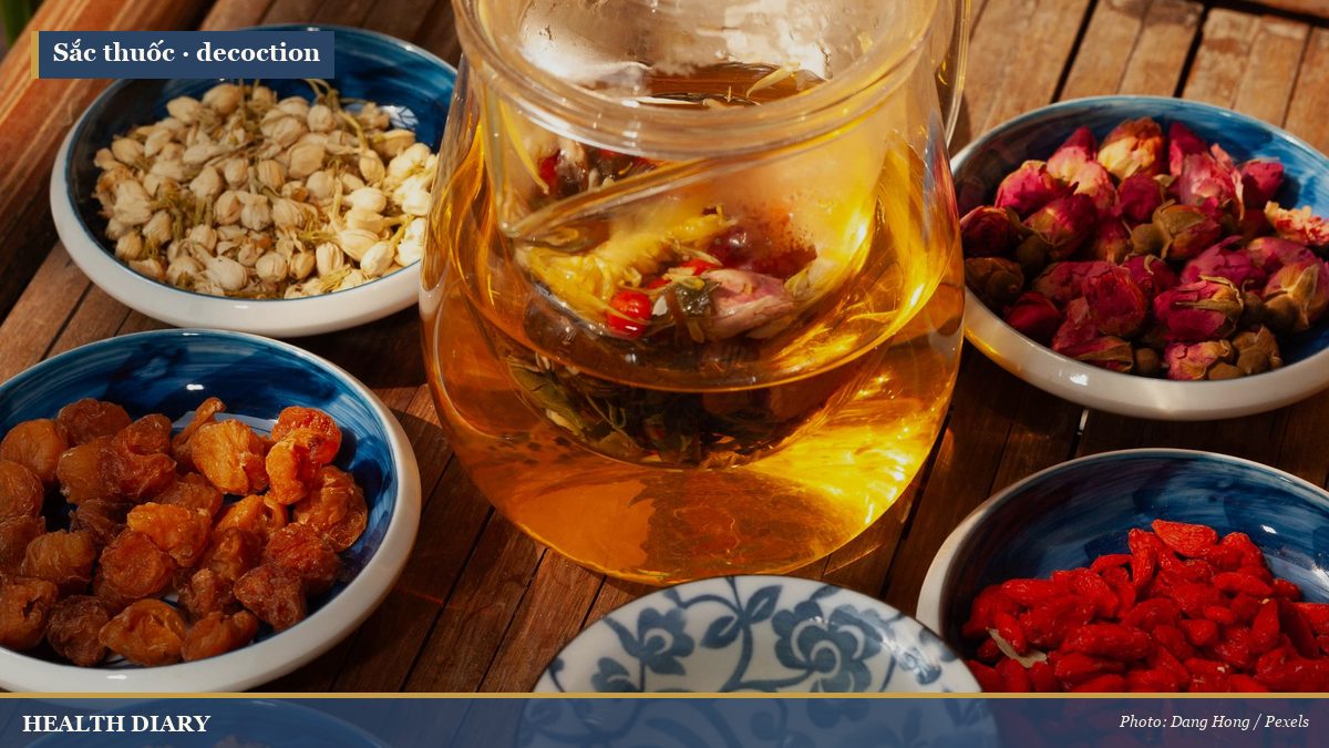 Amber herbal tea and medicinal ingredients brewing in a glass pot