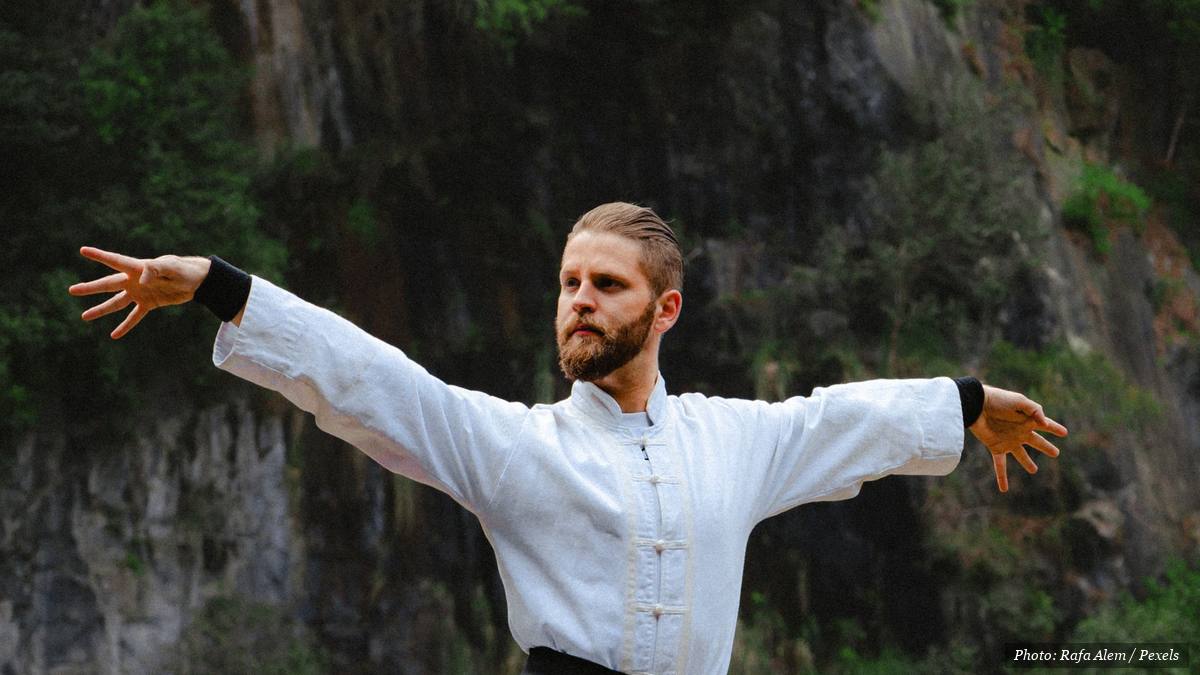 Group practising slow tai chi movements together outdoors in a park