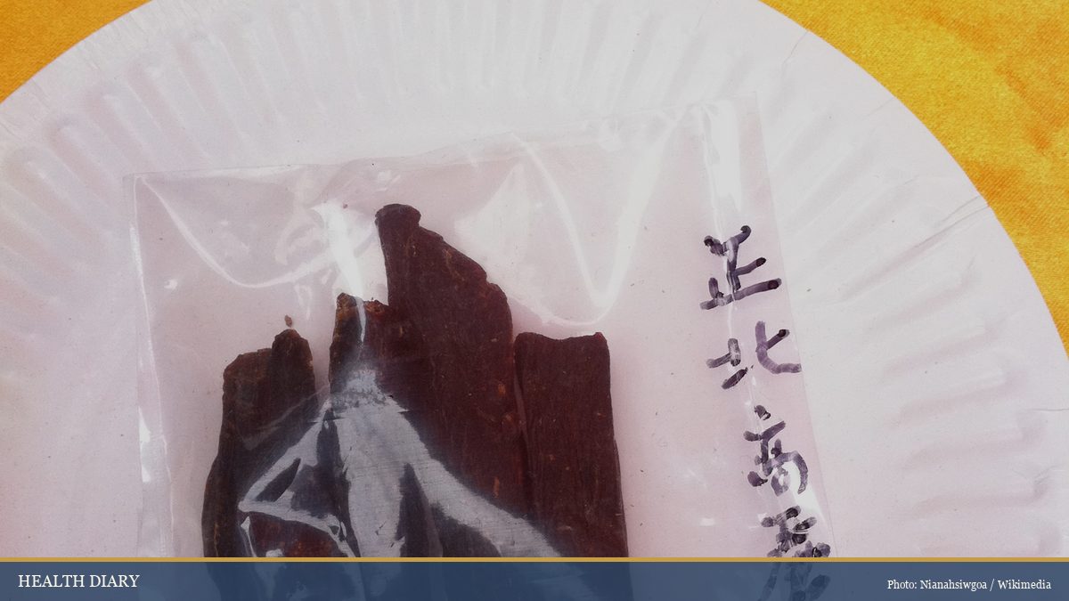 Dried Korean red ginseng slices on a paper plate labeled in Chinese characters at a Hong Kong herb market