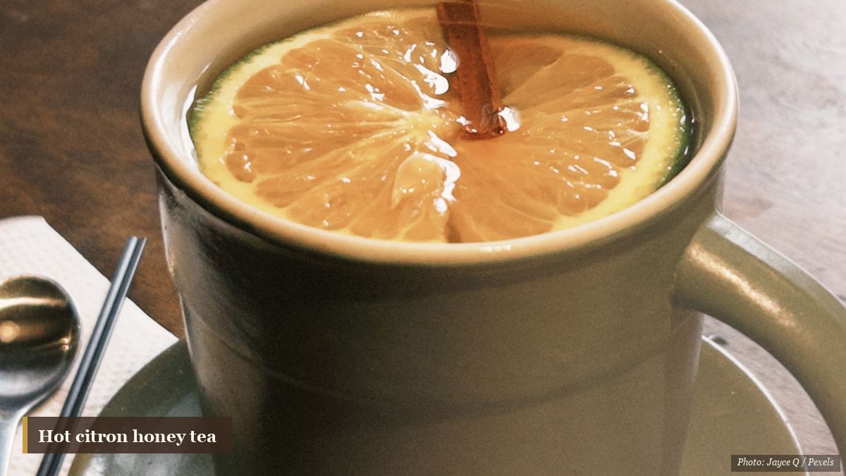 Cozy ceramic mug of hot citron and lemon tea with a cinnamon stick on a wooden table