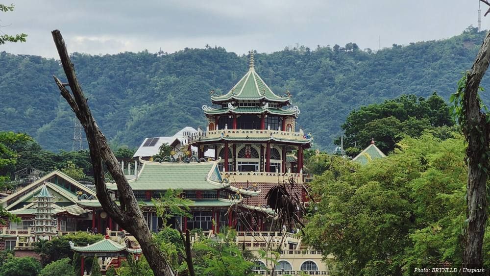 Taoist temple with tiered green roofs rising among forested hills
